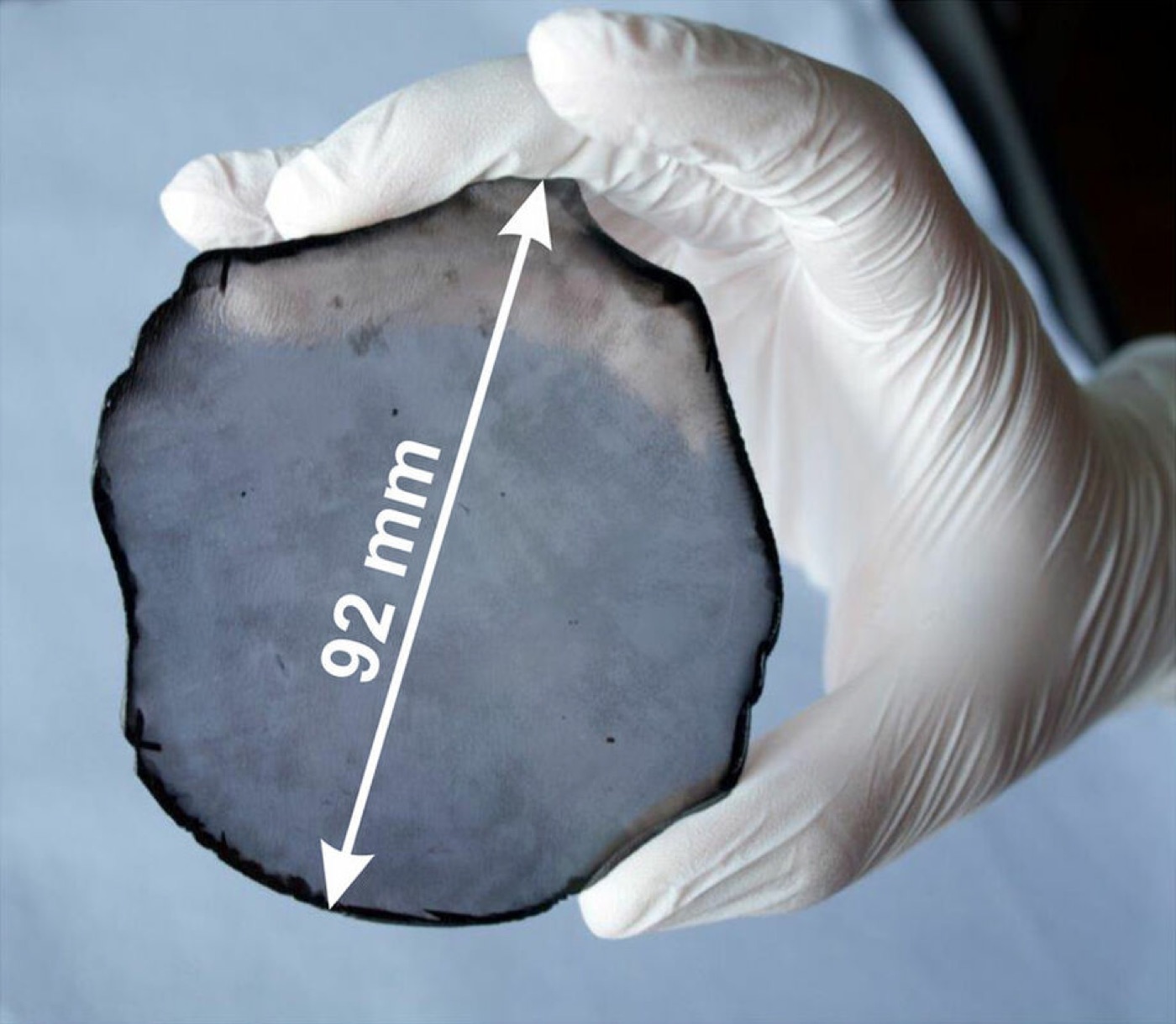 A gloved hand holding a 92 millimetre single crystal CVD diamond disc